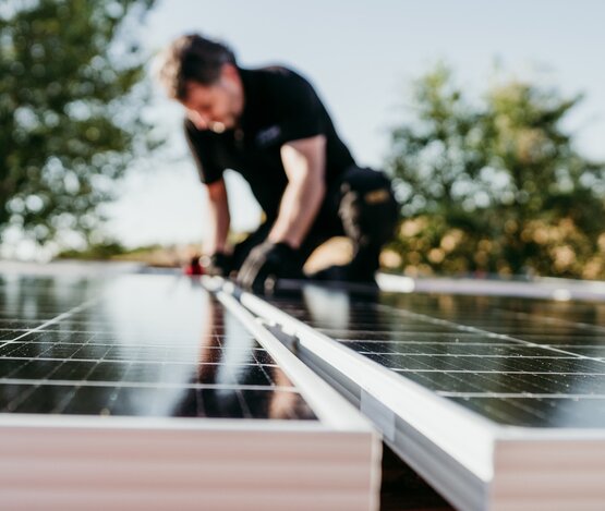 Mann tauscht Solarmodul aus | © iStock/Eva Blanco