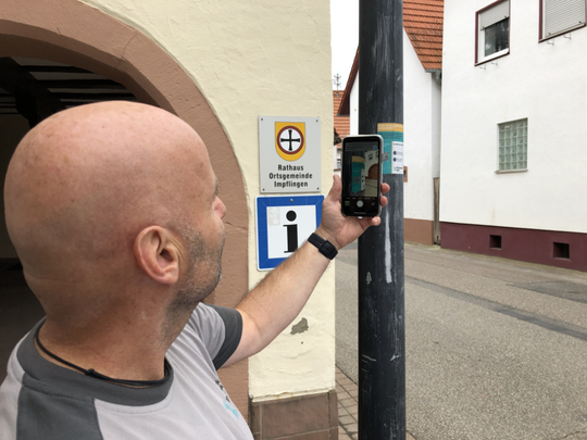 Mann scannt QR-Code an Straßenlaterne