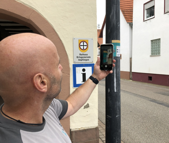 Mann scannt QR-Code an Straßenlaterne